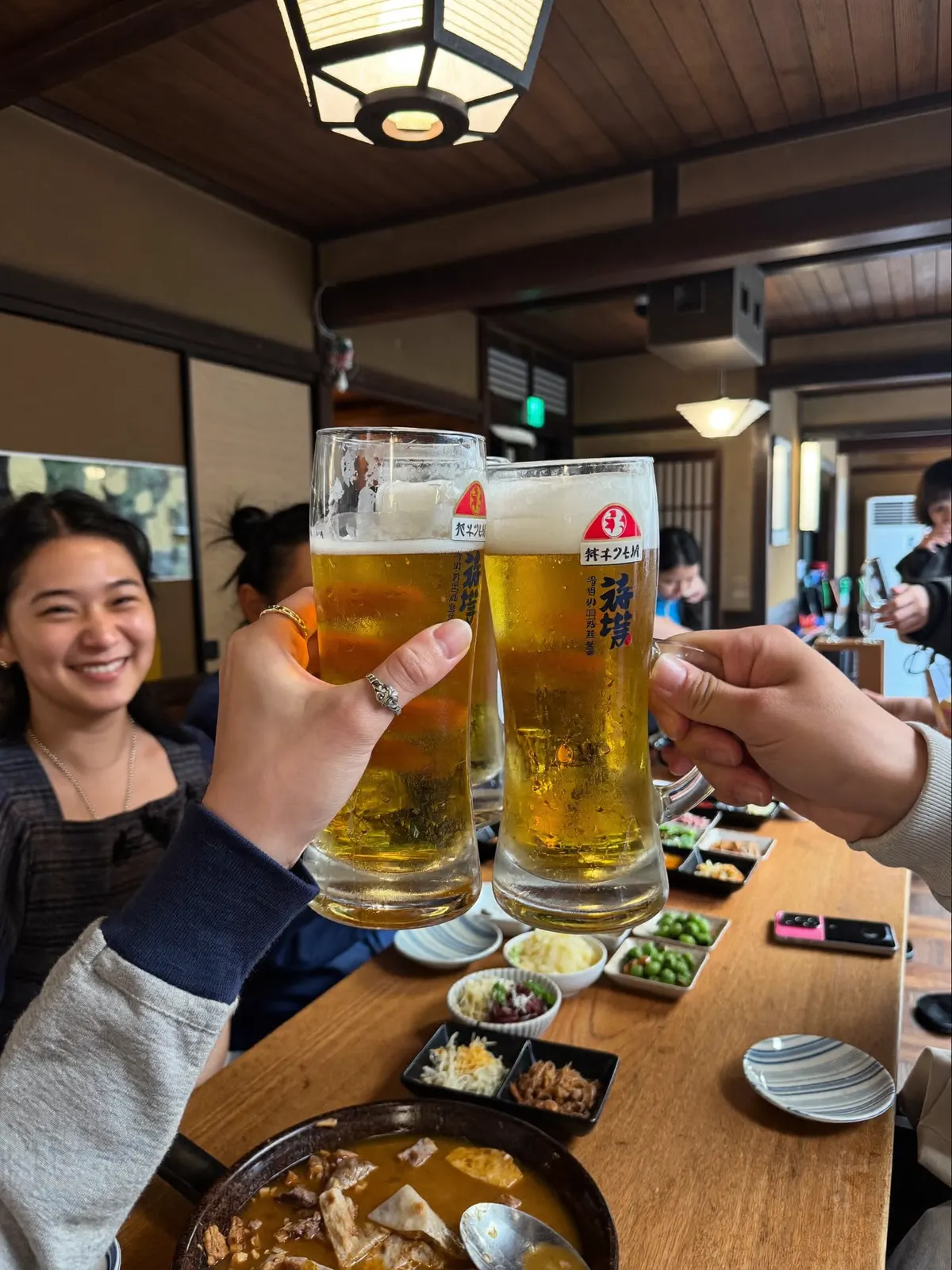 居酒屋の誕生日会でビールで乾杯する友人たち