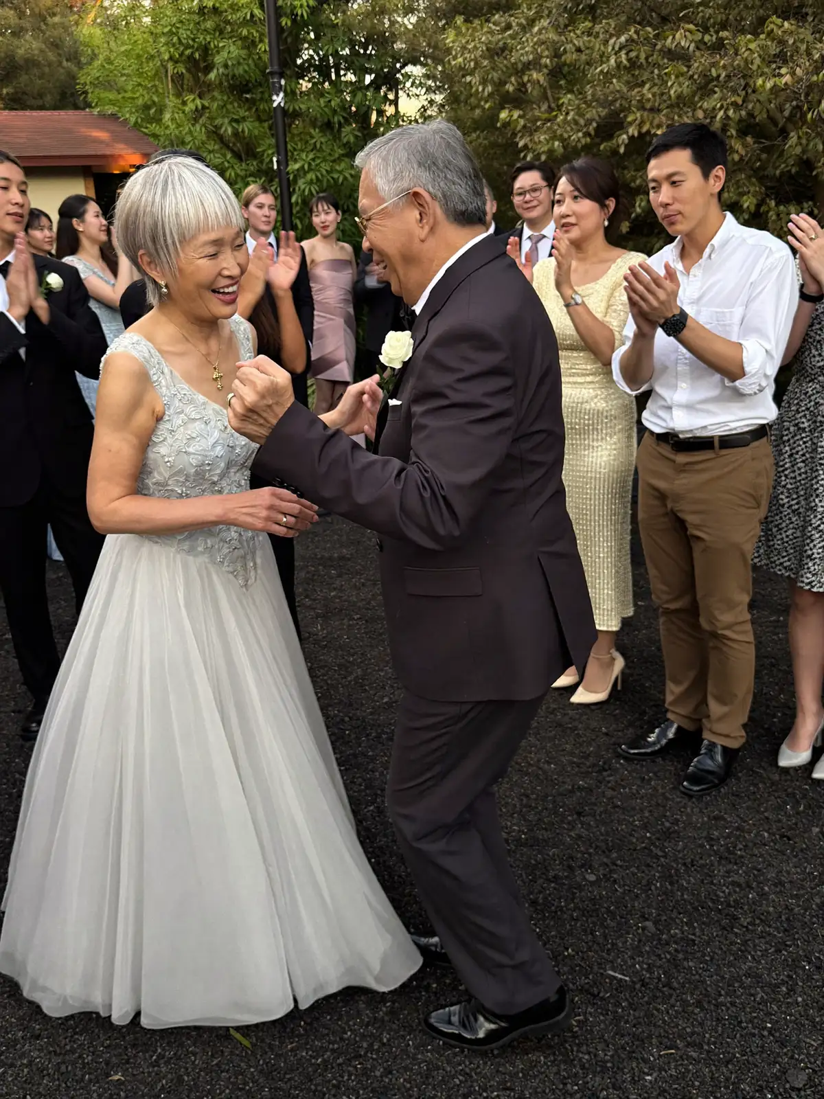 披露宴で踊る年配の夫婦とそれを囲むゲスト