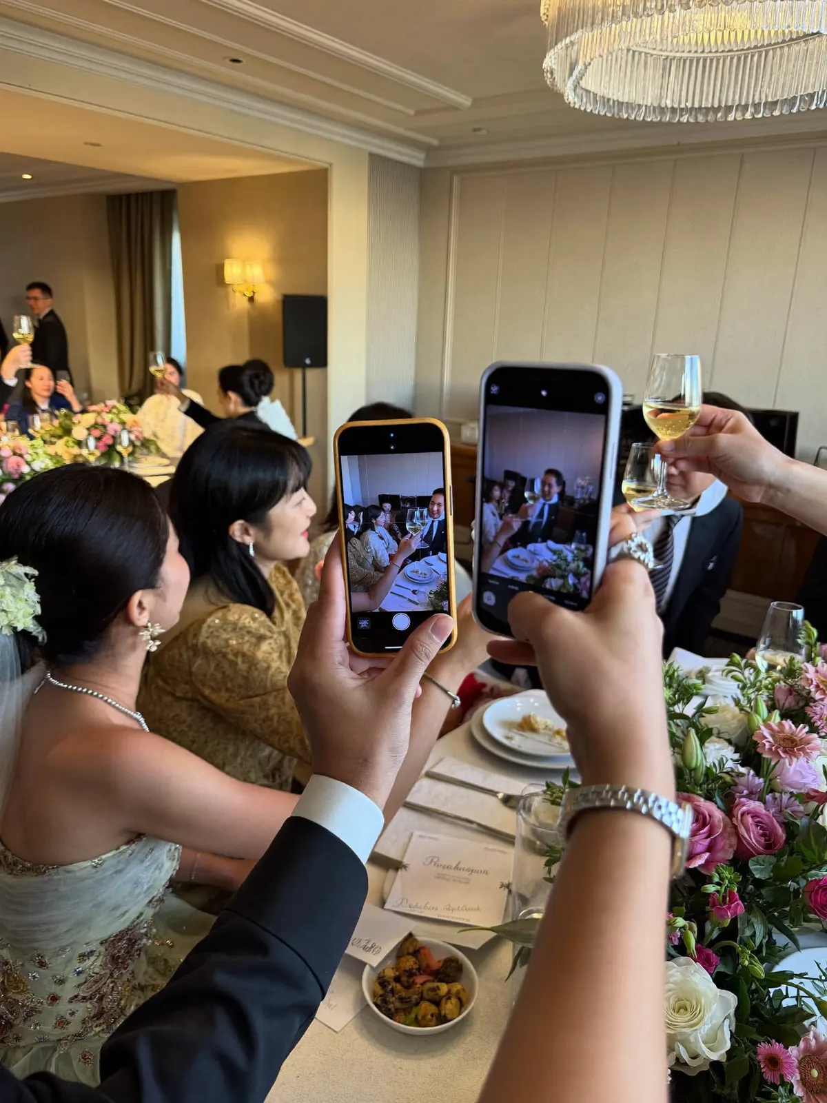 ホテルの披露宴で、ゲストがスマホで乾杯の瞬間を撮影している