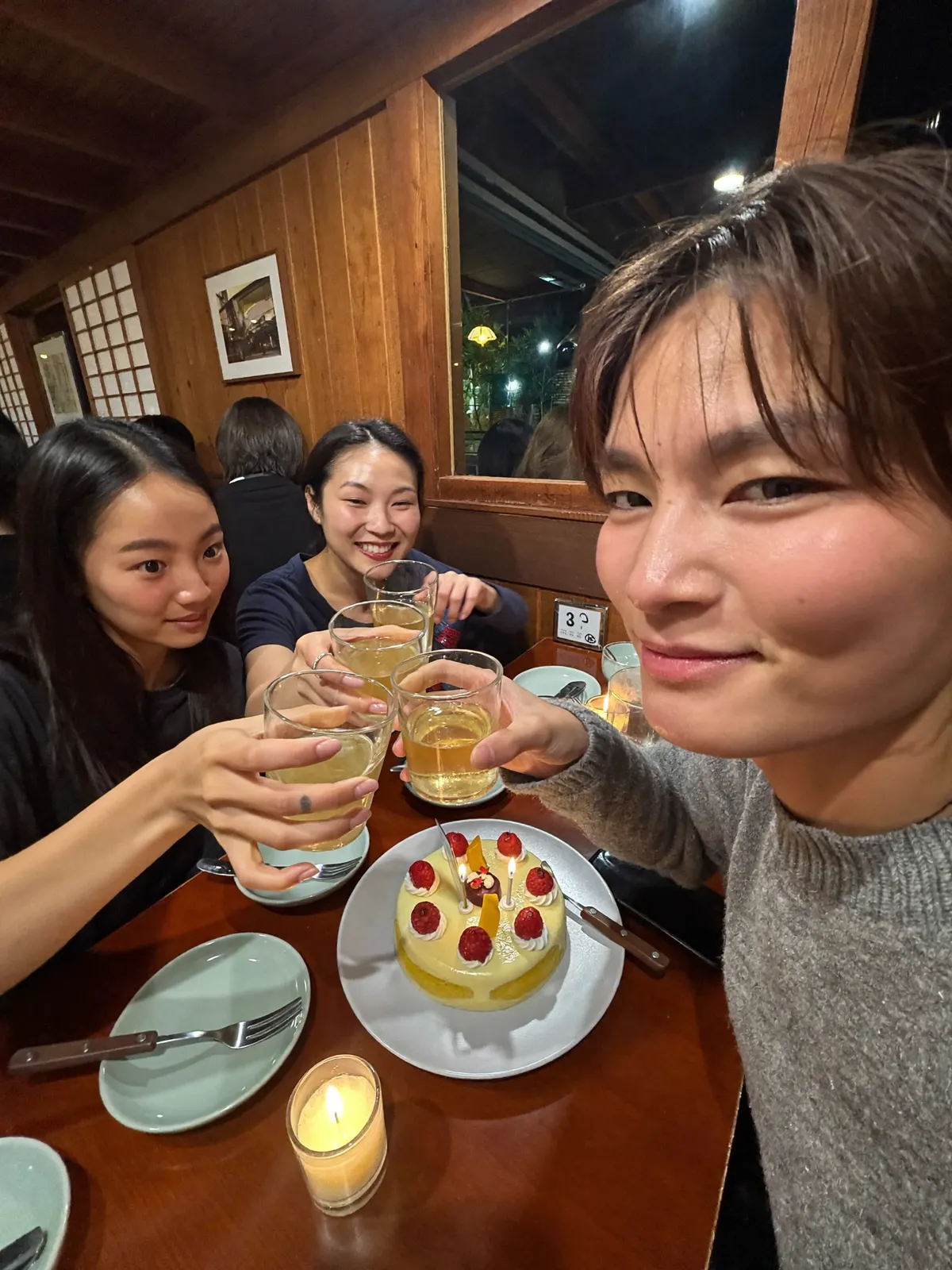 居酒屋でケーキを囲んで乾杯する誕生日会